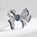Detailed close-up of a bow brooch featuring blue crystals and white diamonds on silver metal - Dark Blue Bowknot