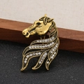 Vista dettagliata di una spilla vintage a testa di cavallo dorata con strass bianchi - Oro Antico