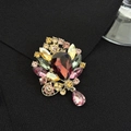 Makroaufnahme einer luxuriösen Vintage-Brosche mit rotem Kristall und bunten Strasssteinen - Luxuriöser Blatt-Stil
