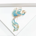 Golden phoenix brooch with light blue enamel wings and sparkling white crystals - Teal
