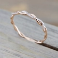 Elegant rose gold twisted rope ring featuring micro-pave diamonds on wood surface - US 6 / Rose Gold