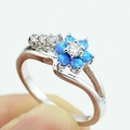 Macro shot of silver floral ring with blue opal petals and sparkling zircon center - US 7 / Blue