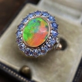 Luxurious rose gold opal ring featuring a halo of blue gemstones on dark velvet - Cy1054 / Size 5