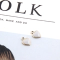 Close-up of white enamel heart charms with gold plating for DIY jewelry making - White