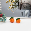 Detailed macro view of orange resin pumpkin charms with green leaves and metal rings - Green Leaf Pumpkin