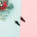 Detailed macro view of two black chili-shaped alloy charms with golden metal ring loops - Black