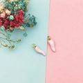 Macro shot of pink enamel chili pendants with gold loops for DIY jewelry making - Pink