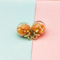 Detail of transparent glass ball charms with orange star sequins and gold metal caps - Orange