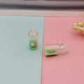 Vue détaillée d'une mini bouteille en verre avec sable vert et petit coquillage blanc - Vert clair
