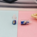 Gros plan d'une mini bouteille dérivante avec sable bleu et coquillage pour bijoux - Bleu clair