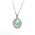 Macro detail of silver round pendant with green fluid heart and sunburst texture - Steel Green