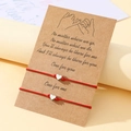 Détail de bracelets de couple en fil ciré rouge avec pendentifs cœur sur carte - Rouge
