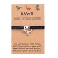 Close-up of handmade woven dinosaur bracelet with heart beads and silver T-Rex charm on card - Black (B00421)
