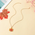 Détail du collier feuille d'érable avec émail rouge-jaune et chaîne à maillons dorés - Feuille d'érable Dorée