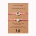 Detalle de dos pulseras trenzadas rosa para madre e hija con dijes de corazón plateados - Rosa