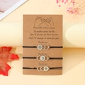 Detailed view of three-piece sun moon and star bracelets on a gift card with dried flowers - Three Circle Style (B00536) / Set of 3 / Black