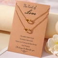 Vue détaillée de deux colliers nœud de cœur dorés avec une carte cadeau à message - Collier Et Carte / Thème Amour Or