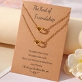 Gros plan de colliers nœud de cœur doré sur une carte cadeau d'amitié en papier kraft - Collier Et Carte / Thème Amitié Or