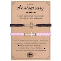 Detailed view of woven couple bracelets with silver cross charms on a gift message card - Anniversary Theme (Black & Pink)