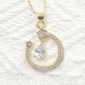 Macro detail of gold-plated moon and star necklace pendant with sparkling zircon stones - White Teardrop Style