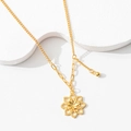 Detail of gold hollow flower pendant with asymmetric chain on white artistic base - Lotus Blossom Necklace