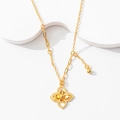 Detail of gold four-petal flower pendant with unique asymmetrical chain on a white stand - Prosperity Bloom Necklace