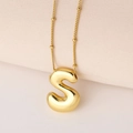 Detail eines polierten goldenen S-Buchstaben-Anhängers mit Perlenkette auf Creme-Stoff - Puffy Goldener Buchstabe S (Nur Anhänger (Ohne Kette))