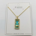 Detail of gold necklace with rectangular blue pendant featuring clover and lucky charms - Lucky Symbol Enamel Square Pendant With Chain And Box