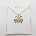Golden crab pendant necklace featuring sparkling cubic zirconia on a white card display - White Zirconia Crab Pendant + Chain + Packaging