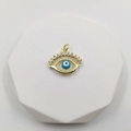 Goldener Evil Eye Anhänger mit Zirkonia-Mikropavé auf weißem geometrischem Ständer - Micro-Pave Wimpernauge-Stil (Augenstil D)