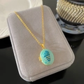 Detail view of a vintage oval locket with blue shell cameo and teal enamel inlay - Light Cyan Locket Shell Style (W969)
