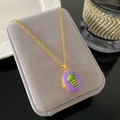 Close-up of golden locket necklace with purple enamel inlay on a velvet jewelry display - Purple Enamel Locket Style (W971)