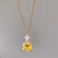 Macro view of gold chain necklace featuring a square yellow gem with halo diamonds - Yellow