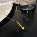Detailed close-up of golden five-star tassel necklace with micro-set zircons on black gloss - Five Star Rhinestone Necklace (X2027)