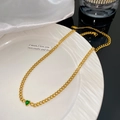 Detail of a golden Cuban link necklace with a sparkling green heart-shaped gemstone - Single Green Heart Pendant Necklace (X2169)