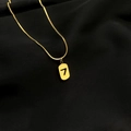 Detailed close-up of golden snake chain and rectangular lucky number 7 pendant on black silk - Gold - Lucky 7