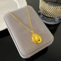 Colgante de relicario ovalado dorado con relieve y mariposa verde sobre joyero gris - Estilo Relicario Figura en Relieve (W994)