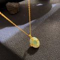 Golden necklace with oval green gemstone pendant and fine wirework on stone background - Gold Necklace Green Cat Eye (W1025)