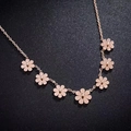 Collier marguerite en or rose avec sept pendentifs floraux sur fond noir texturé - Motif Marguerites Multiples / Or rose