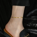 Minimalist gold snake chain anklet for women shown on ankle with elegant black silk background - 4mm Blade Chain (B10088)