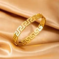 Golden titanium steel bangle featuring an intricate Greek key pattern on satin fabric - Greek Key Bracelet / Gold