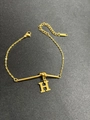 Makroaufnahme der goldenen Knotenkette mit H-Buchstabenanhänger und verstellbarem Verschluss - Buchstabe H