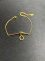 Detail eines goldenen Titanstahl-Armbands mit zartem Buchstaben-O-Anhänger und Karabiner - Buchstabe O