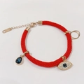 Red woven cord bracelet with gold charms and a blue pear-shaped stone detail - Rose Gold Red Evil Eye Bracelet
