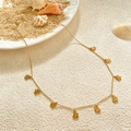 Macro shot of gold-plated clover pendant necklace on beach sand with shells - Lucky Clover Necklace / Gold