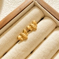 Detailed view of dainty gold bee stud earrings on a premium wooden jewelry box tray - Bee Studs / Gold