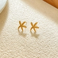 Macro detail of gold starfish earrings with textured surface on a minimalist background - Gold Little Starfish
