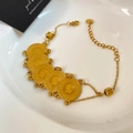 Detail view of gold layered titanium steel bracelet with coin pendants on a ceramic tray - Gold Portrait Layered Five Round Coin Style (YMX1688-1)