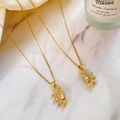 Colliers pendentifs soleil dorés avec zircons sur marbre, vue sous un angle de 45 degrés - Style de Soleil Magnétique Assorti