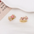 Detailed macro of gold plated enamel rocking horse charms on white silk fabric - White